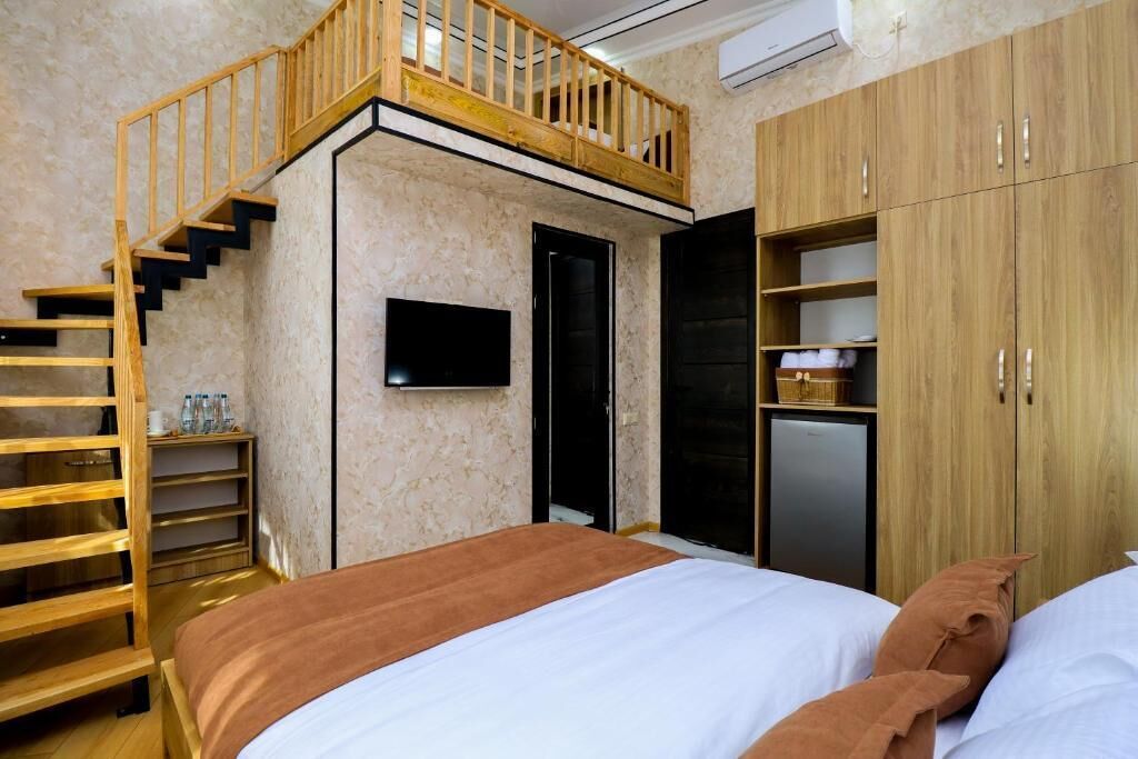 Une chambre à coucher avec un lit, un escalier en bois, une armoire et un téléviseur.