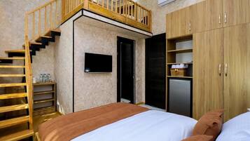 Une chambre à coucher avec un lit, un escalier en bois, une armoire et un téléviseur.