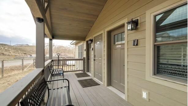 A covered porch with a bench, a door, and a window.