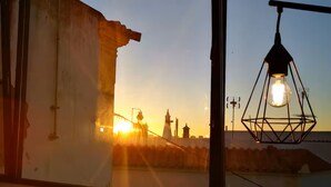 Una habitación con un amplio ventanal que da a una vista urbana al atardecer.
