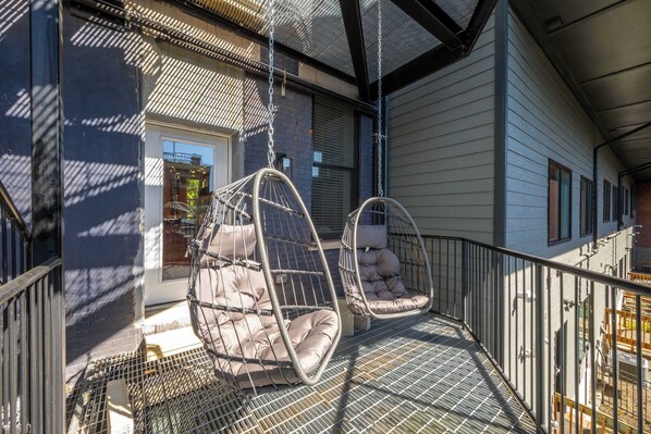 Ein Balkon mit zwei Hängestühlen und einem Metallgeländer.
