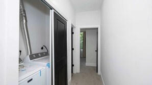 A laundry room with a washer and dryer, a vent, and a hallway leading to another room. - Heights on Wayne by Blackhouse (Cincinnati)
