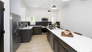 A modern kitchen with dark cabinetry, stainless steel appliances, and pendant lighting. - Heights on Wayne by Blackhouse (Cincinnati)