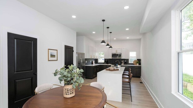 A modern kitchen with a central island, black cabinets, and stainless steel appliances. - Heights on Wayne by Blackhouse (Cincinnati)