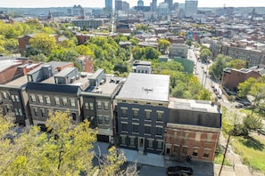 A cityscape with a mix of residential and commercial buildings, including a prominent red brick building with a flat roof and a large mural on the side. - Queen City Views 2 Sleeps 2! (Cincinnati)