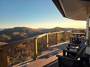 Une terrasse en bois dotée d’une balustrade, d’où l’on peut admirer un paysage montagneux.