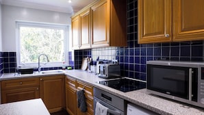 Eine Küche mit Holzschränken, einer Granitabdeckung, einer Spüle, einem Toaster, einer Mikrowelle und einem Backofen.