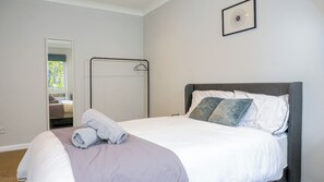 A neatly made bed with white and grey bedding, a grey headboard, and two pillows. A towel is folded on the bed. - Apartmentsleeps3-balcony-valleyview-parking (Hemel Hempstead)
