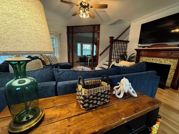 A living room with a blue sofa, a wooden coffee table, a green vase, a woven basket, and a white octopus figurine.