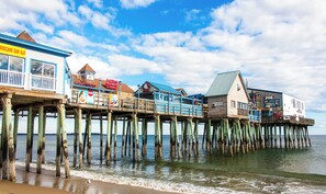 A wooden pier with multiple buildings, including a bar and a restaurant, extending into the water.