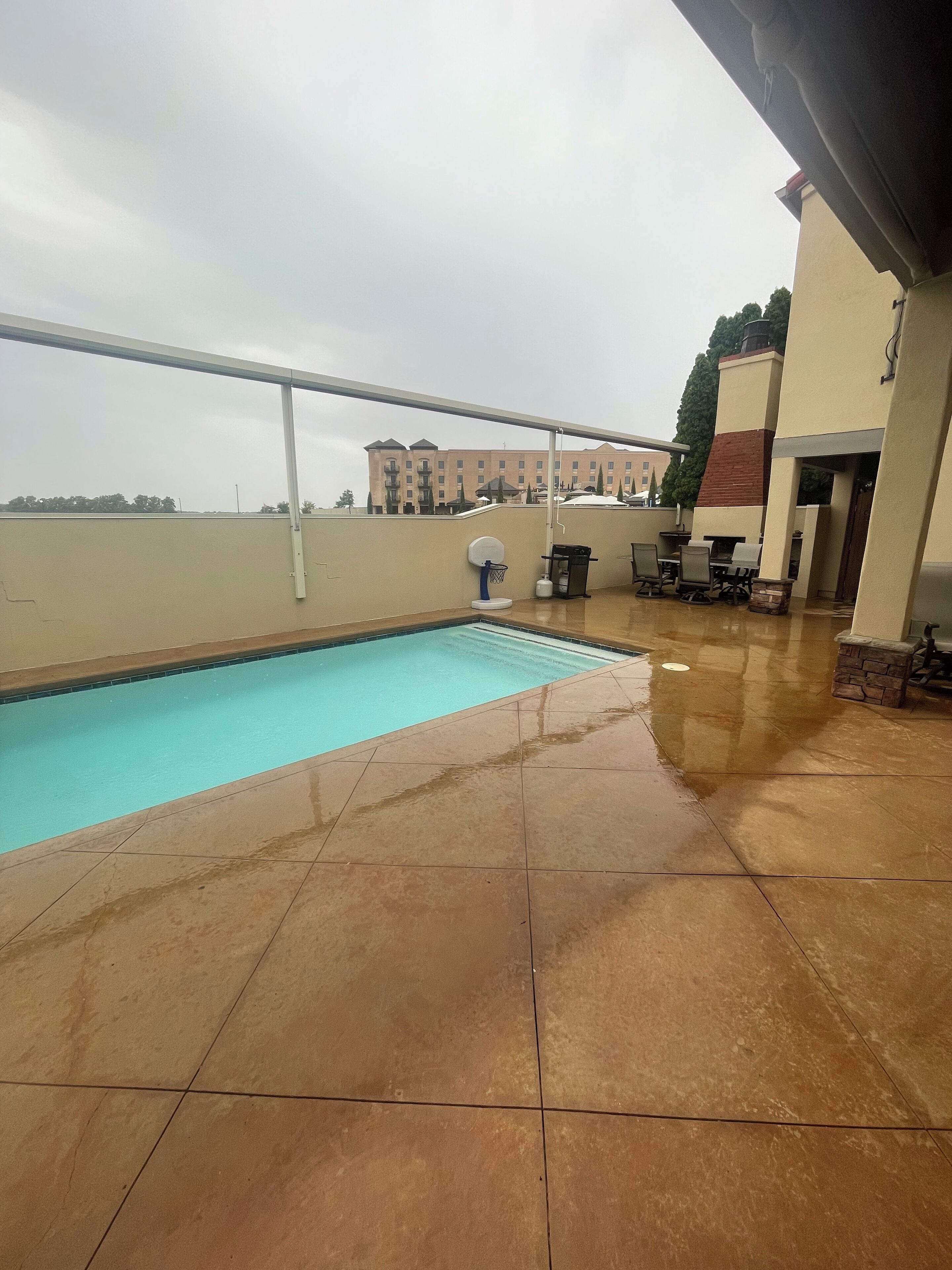 Un área de piscina en la azotea con vistas despejadas a un edificio al fondo.