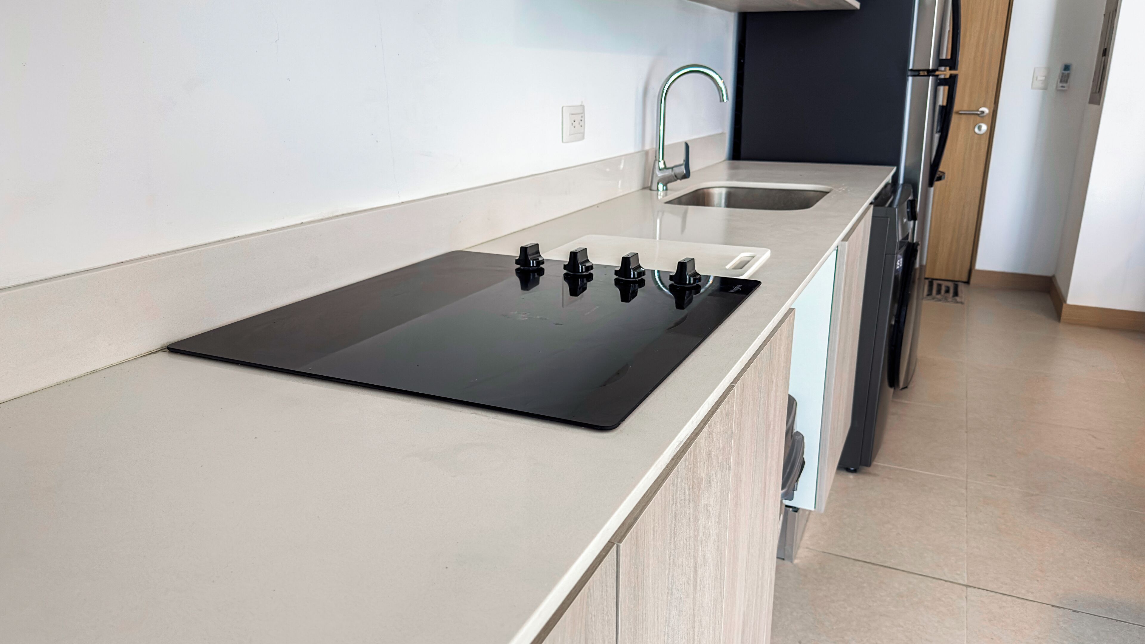 A modern kitchen with a black induction cooktop, two sinks, and a stainless steel faucet.