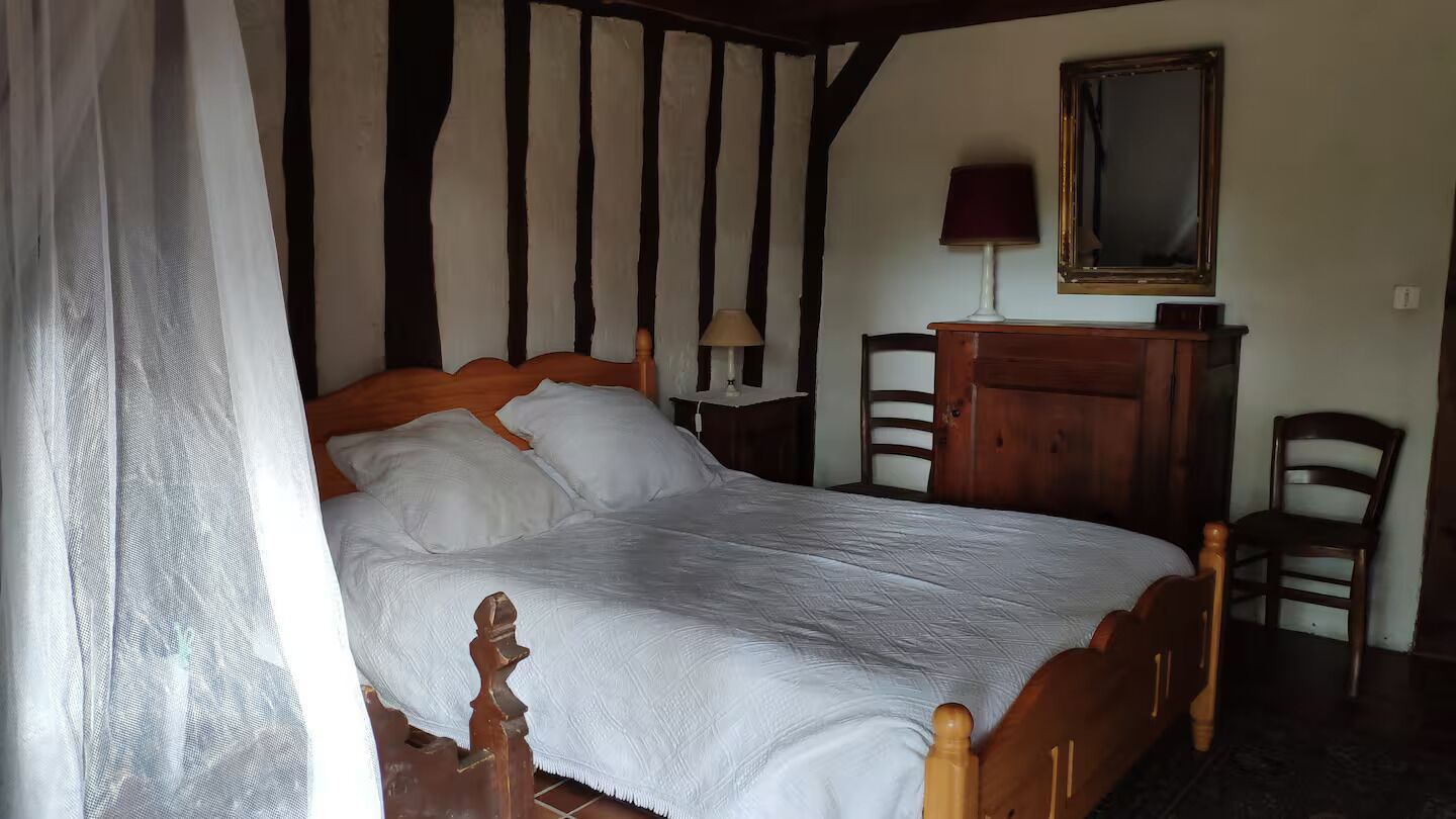 Une chambre à coucher avec un lit en bois, une table de chevet, une lampe, un miroir et deux chaises.