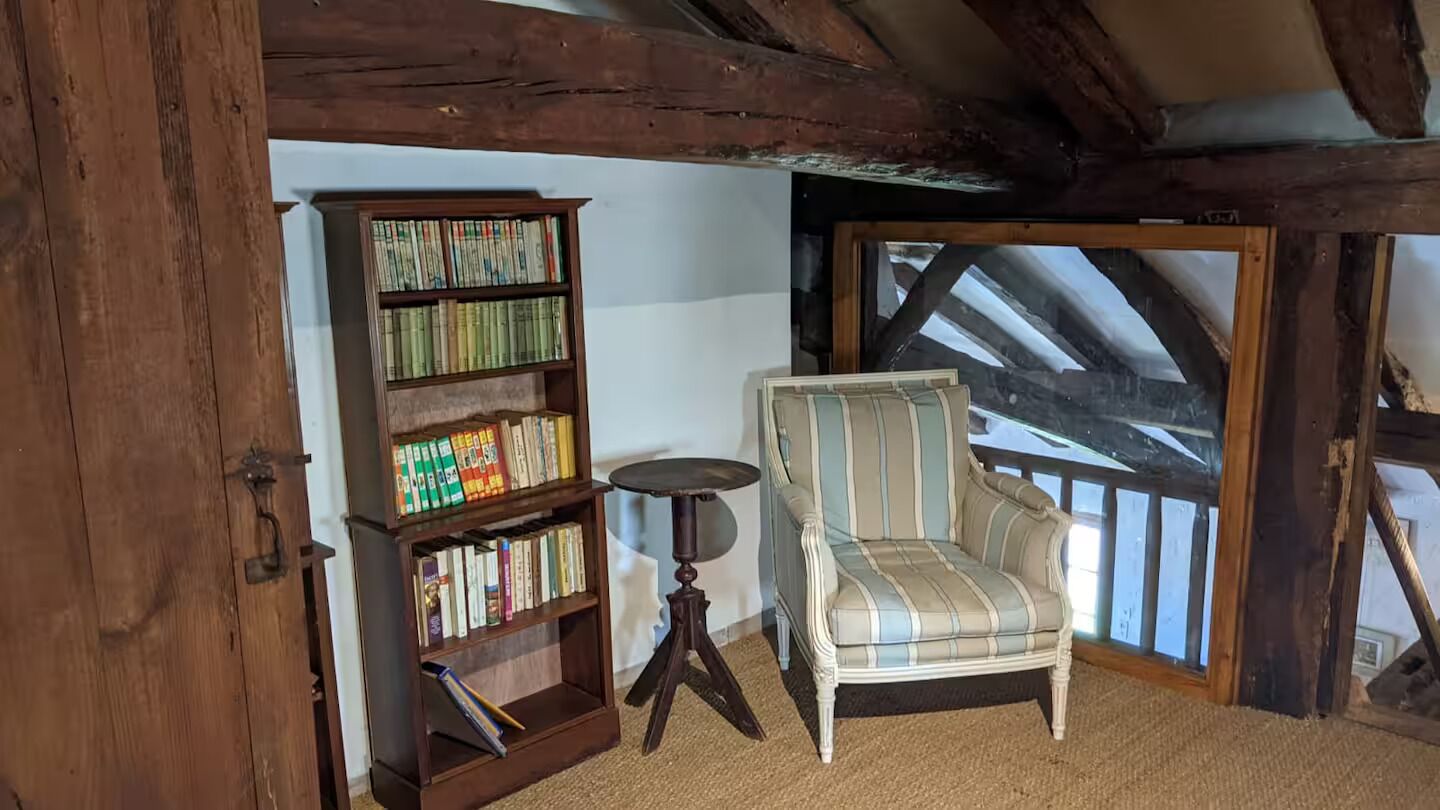 A cozy reading nook with a wooden bookshelf, a striped armchair, and a small round table.