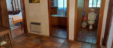 Una habitación con cama, radiador, un cuadro y baño con inodoro y ventana.