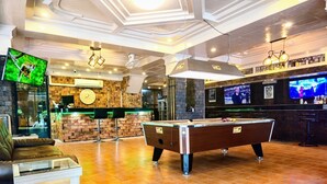 A billiards table in a room with a brick wall, a bar area with a TV, and a seating area with a sofa and a table. - Patong Rockshore  (Patong)