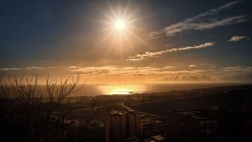 Ein Sonnenuntergang über einer Küstenstadt, im Vordergrund befinden sich Gebäude.