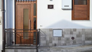 A building entrance with a wooden door, a metal gate, and a window with wooden shutters.