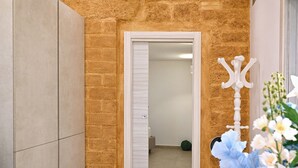 A modern room with a stone accent wall, a white door, a blue sofa, and a white chair.