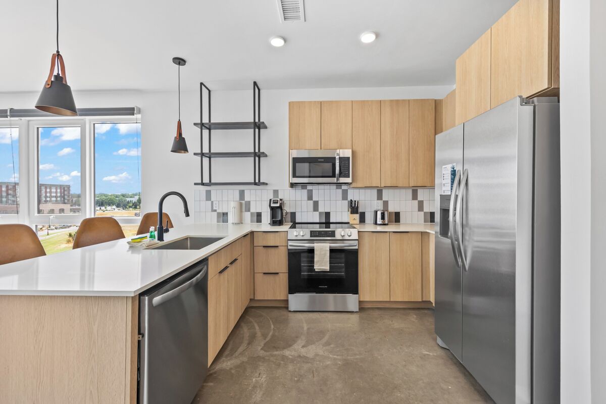 Una cocina moderna con una isla central, electrodomésticos de acero inoxidable y vistas a la ciudad.
