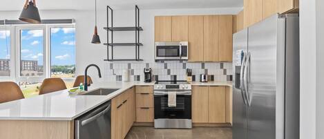 Una cocina moderna con una isla central, electrodomésticos de acero inoxidable y vistas a la ciudad.