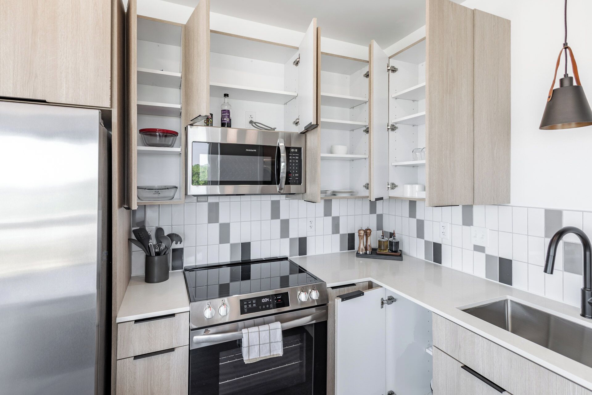 A modern kitchen with a built-in microwave, oven, and stainless steel countertops.