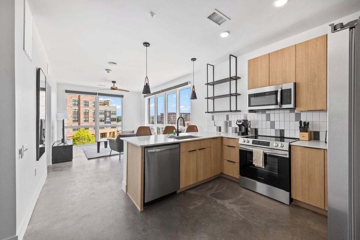 A modern kitchen with a dishwasher, stove, microwave, and wooden cabinets.