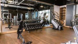 Una palestra con attrezzature per esercizi, uno specchio a parete e un pavimento in legno.