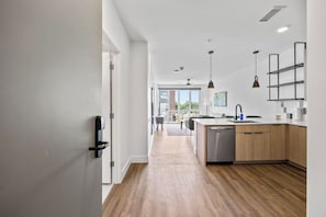 Une cuisine moderne avec des meubles en bois, un lave-vaisselle et des luminaires suspendus.