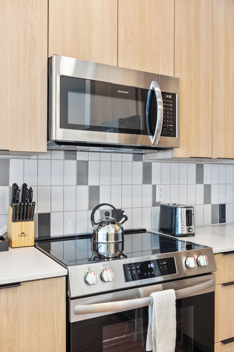 A modern kitchen with a stainless steel microwave, a gas stove, and a toaster.
