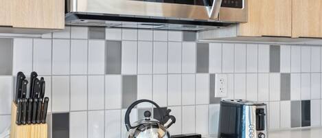 Una cocina moderna con un microondas de acero inoxidable, una estufa a gas y un tostador.