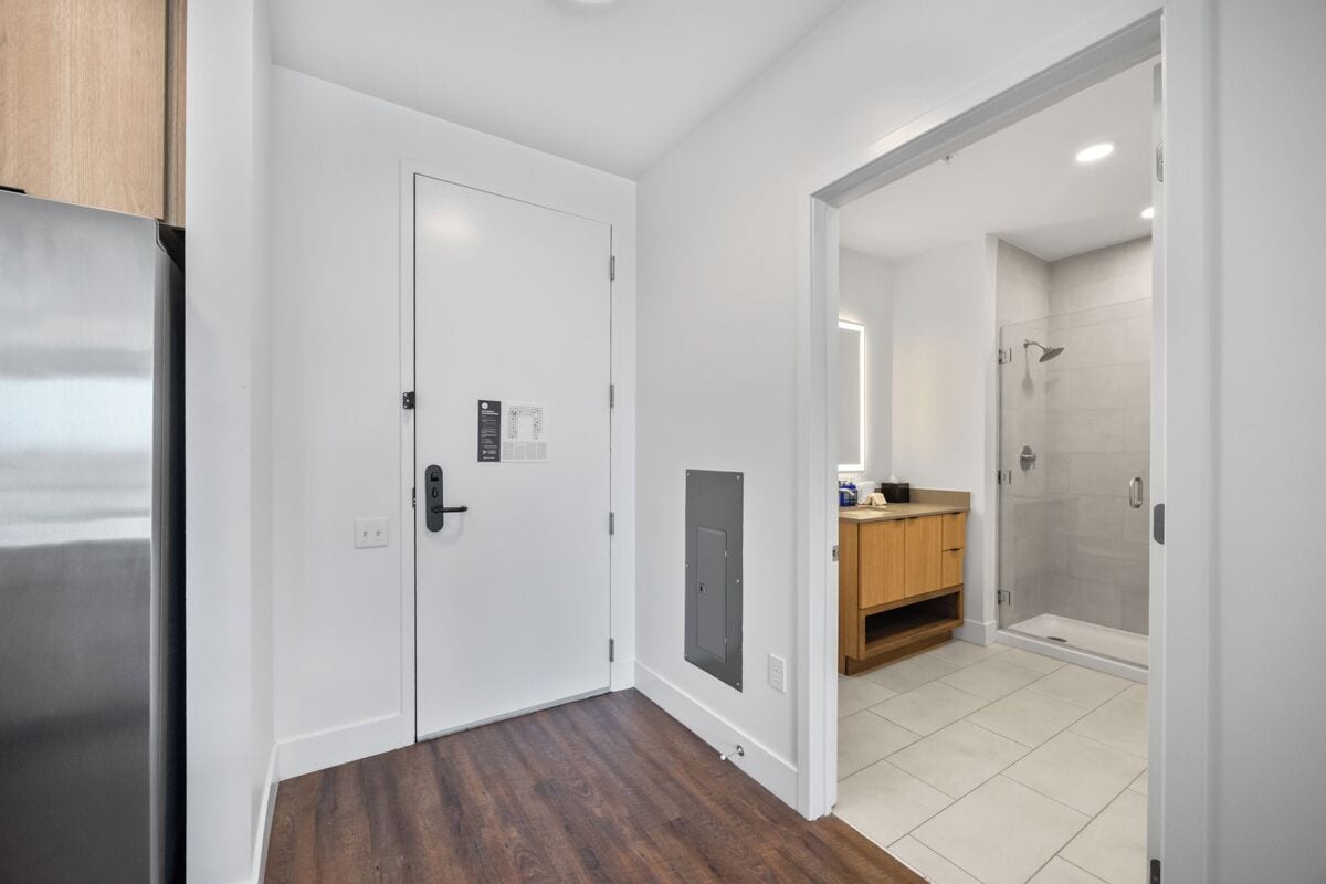 Una cocina moderna con un refrigerador de acero inoxidable, una puerta blanca con manija y un armario de madera.