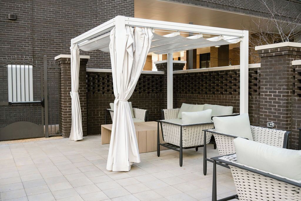 An outdoor seating area with wicker furniture and a white canopy.