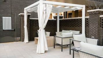 An outdoor seating area with wicker furniture and a white canopy.