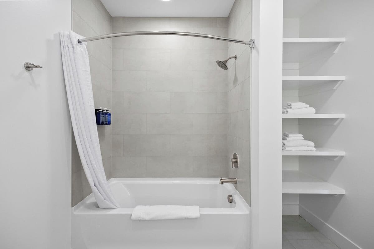 A modern bathroom with a walk-in shower, a bathtub, and built-in shelves for towels.