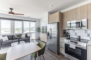 Une cuisine moderne équipée d’un réfrigérateur, d’un four et d’un four à micro-ondes. Un coin repas avec une table et des chaises est également disponible.