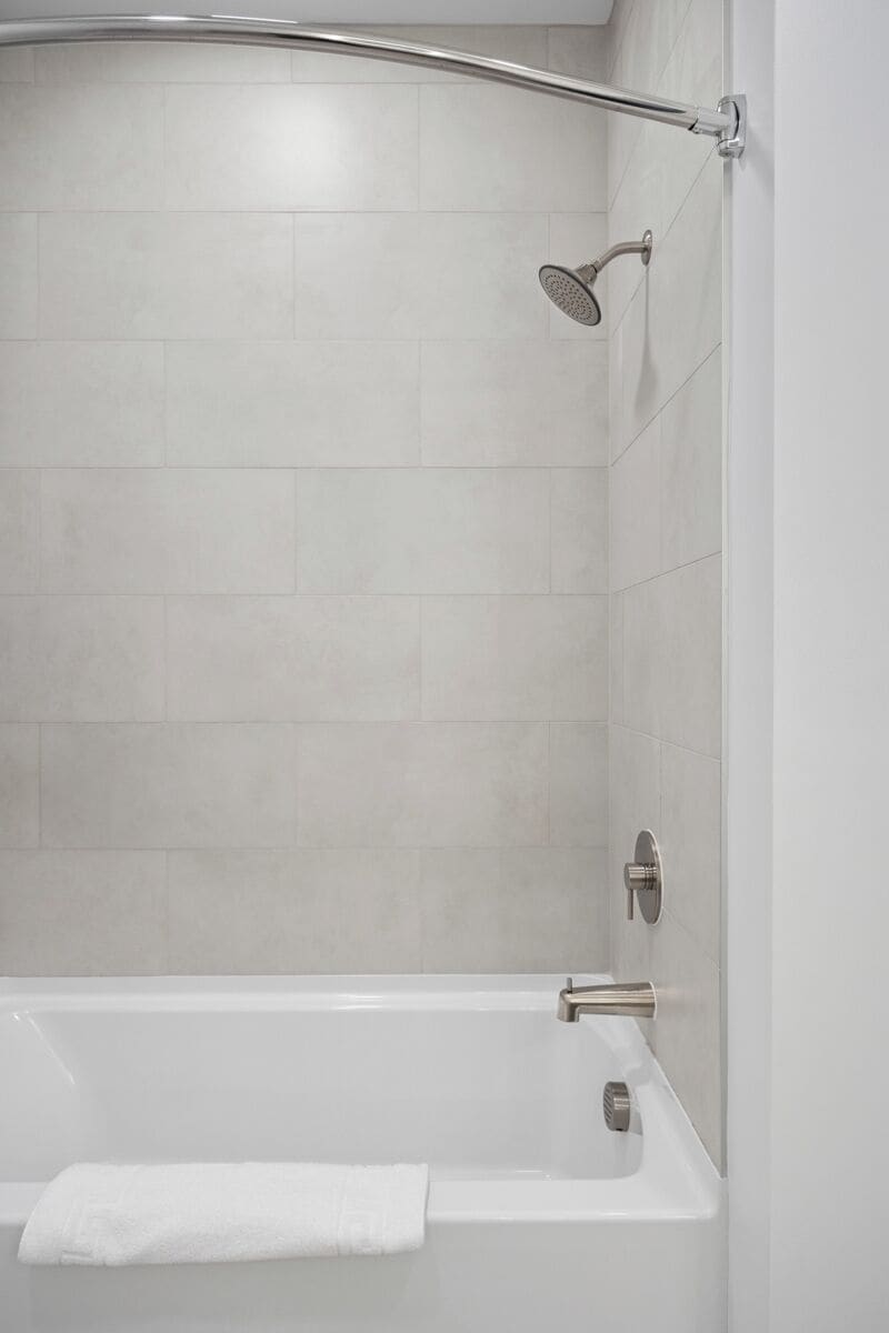 A modern bathroom with a shower, a bathtub, and a towel rack.