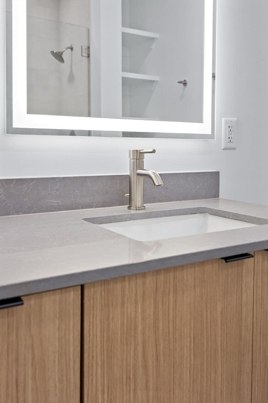 A bathroom with a modern sink, a mirror, and a shower.