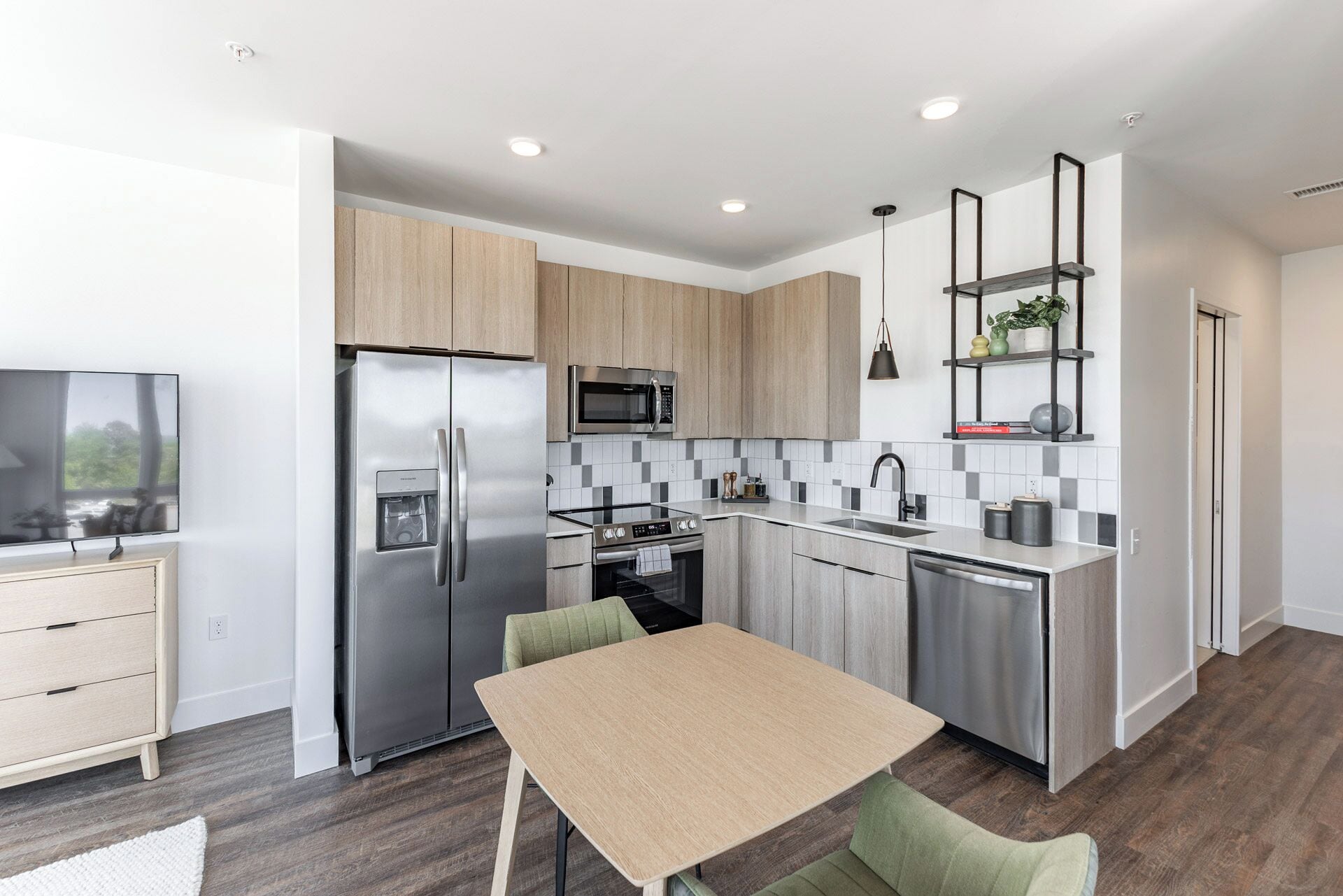 A modern kitchen with stainless steel appliances, a dining area with a table and chairs, and a built-in oven.
