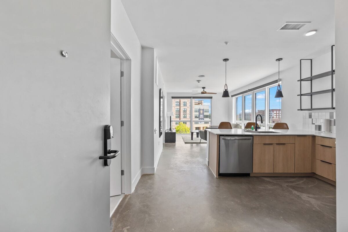 A modern kitchen with a dishwasher, wooden cabinets, and a large window.