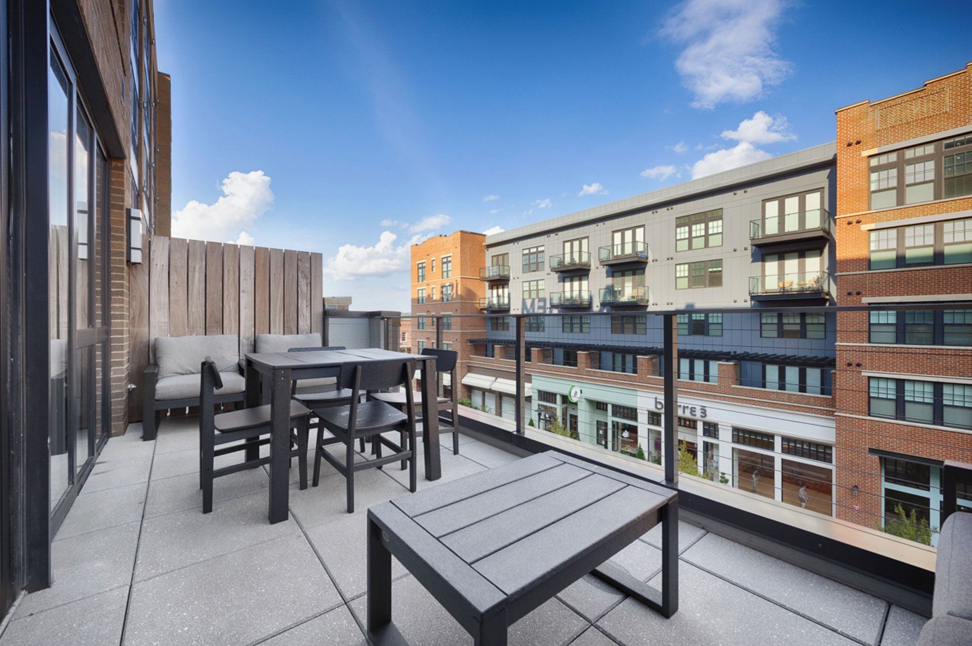 A rooftop terrace with outdoor seating and a view of adjacent buildings.