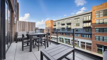 A rooftop terrace with outdoor seating and a view of adjacent buildings.