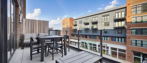 A rooftop terrace with outdoor seating and a view of adjacent buildings.