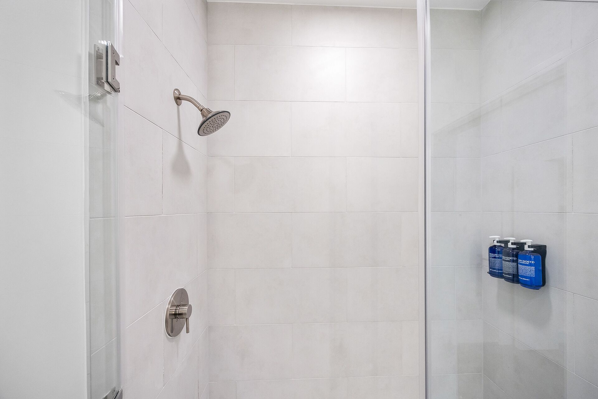 A modern shower with a handheld showerhead and a wall-mounted control panel.