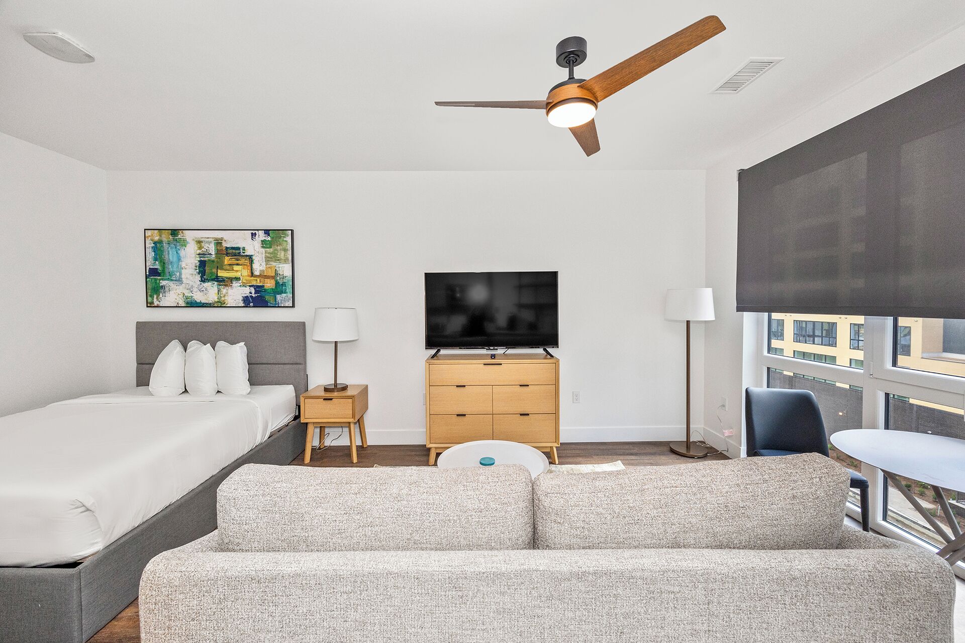 Habitación de hotel con cama, sofá, televisión, escritorio y ventana con vistas.