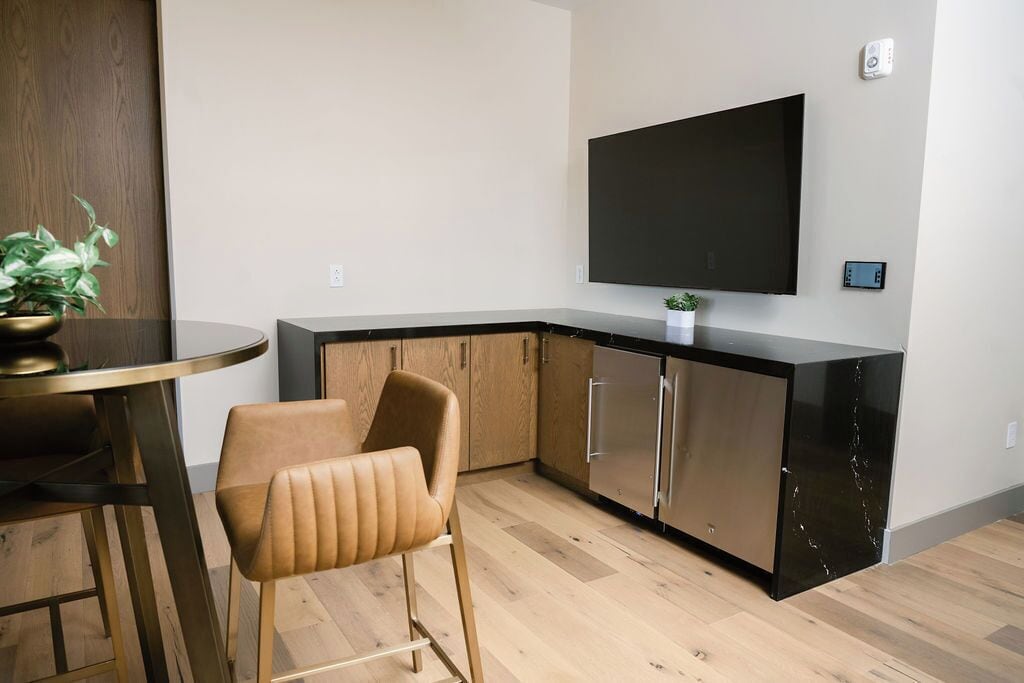 Una cocina moderna con televisor de pantalla plana, armarios de madera y un comedor con una silla y una mesa.