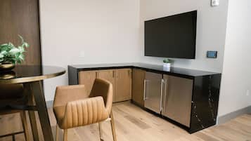 Una cocina moderna con televisor de pantalla plana, armarios de madera y un comedor con una silla y una mesa.