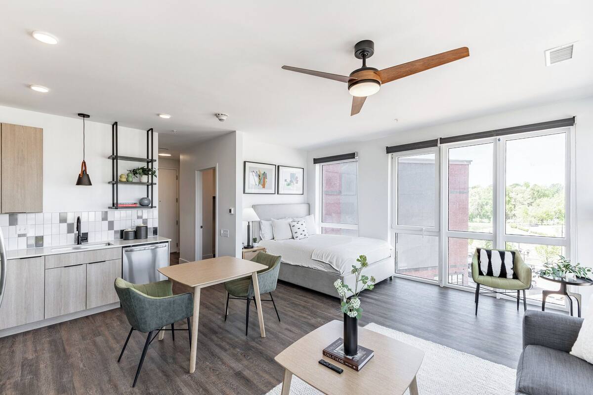 Une pièce moderne et bien éclairée, comprenant un lit, une table à manger et un coin cuisine.