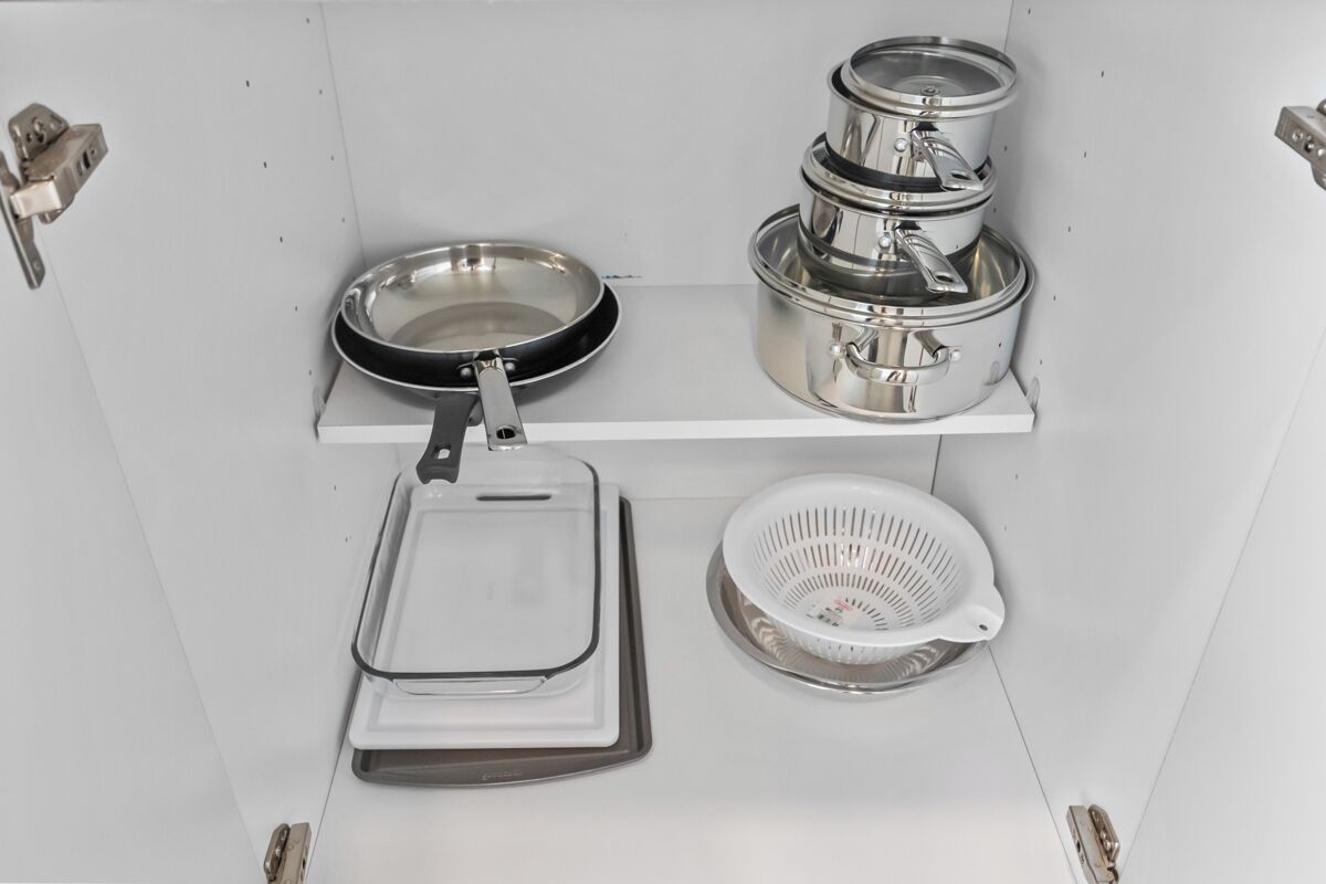 Une cuisine équipée d’ustensiles de cuisine en acier inoxydable, notamment une poêle, des casseroles et une passoire.