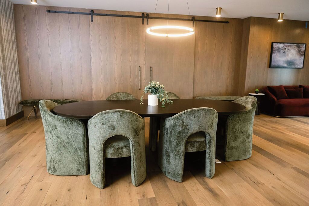 Un comedor con una mesa redonda y seis sillas tapizadas.